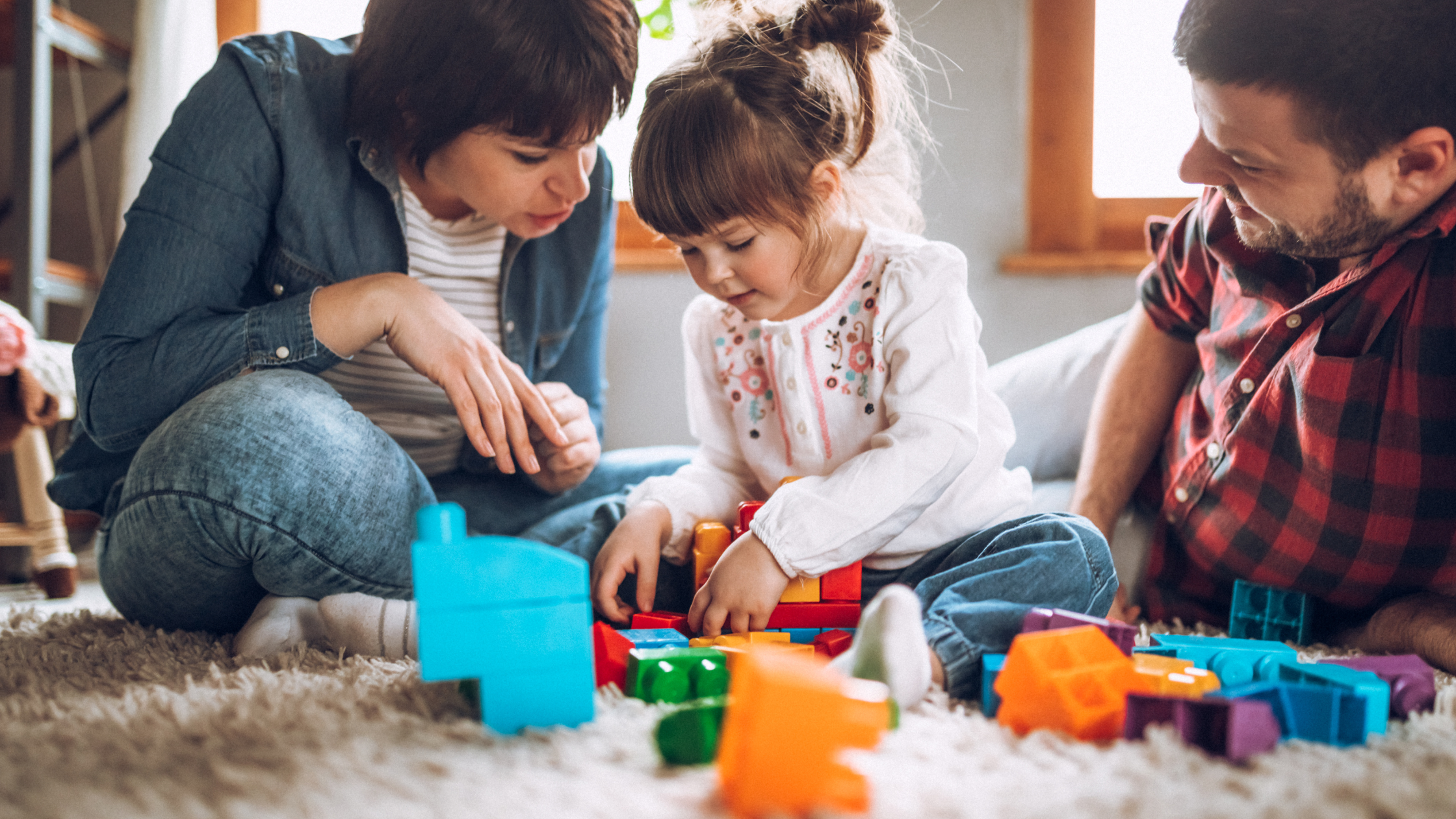 Parents working on motor and play skills with their child with an Autism Spectrum Disorder (ASD) diagnosis.