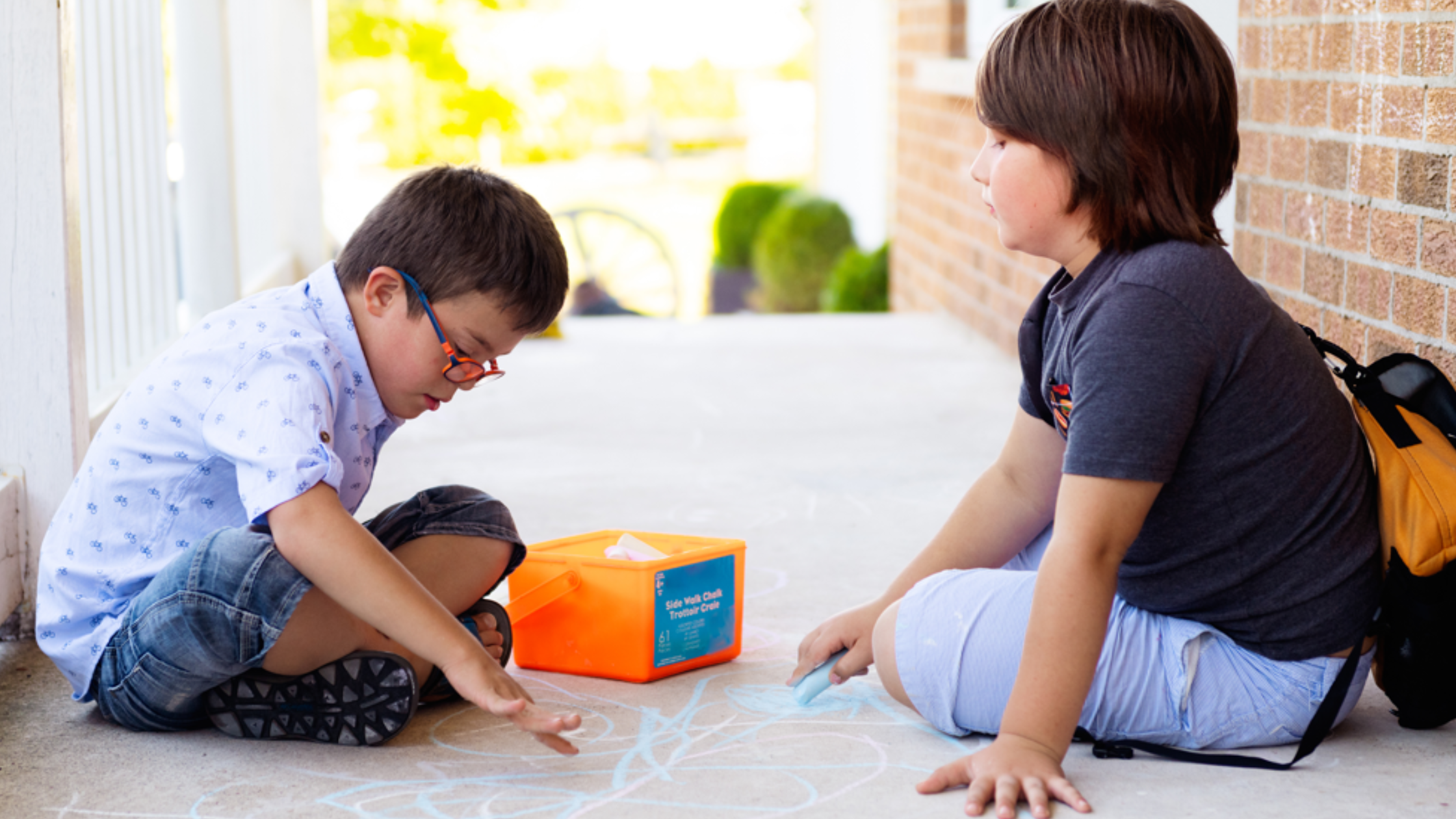 A boy with autism and his brother playing with chalk together.
