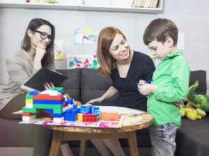 A parent, BCBA, and child with autism discussing ABA therapy