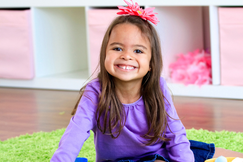 Smiling young child on the floor in a classroom.