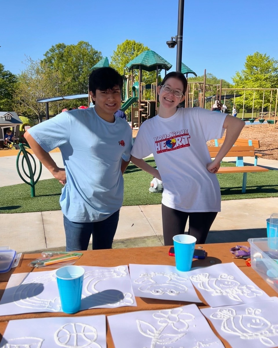 Two happy people standing at a craft table at a city park.