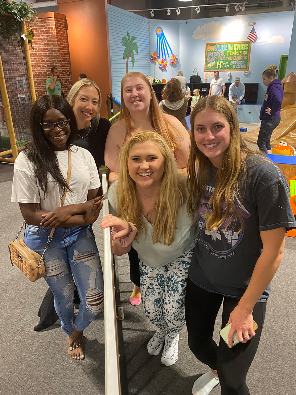 Smiling coworkers stand inside play area.