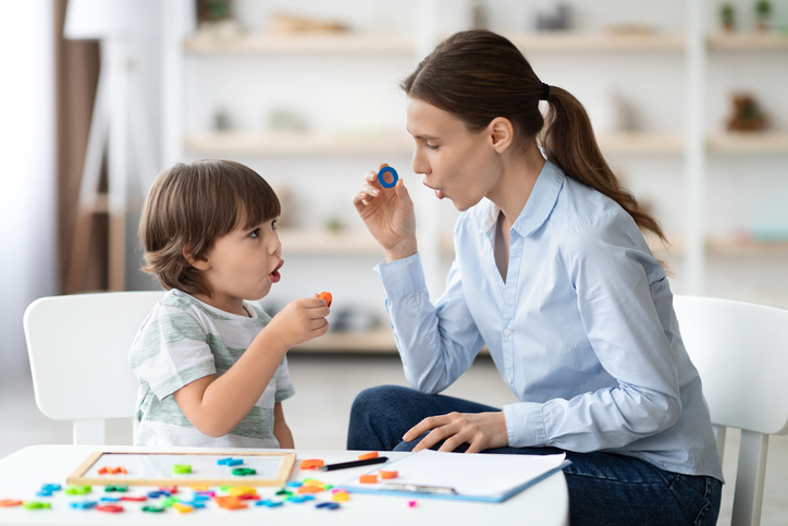 Mom and son playing with colorful letters at a table.