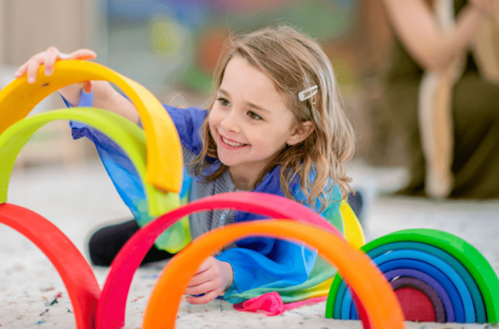 Young child playing with colorful toys on the floor.