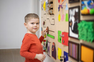 Child plays with wall mounted sensory toy.