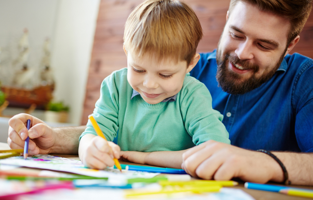 Father and son coloring together at a table.