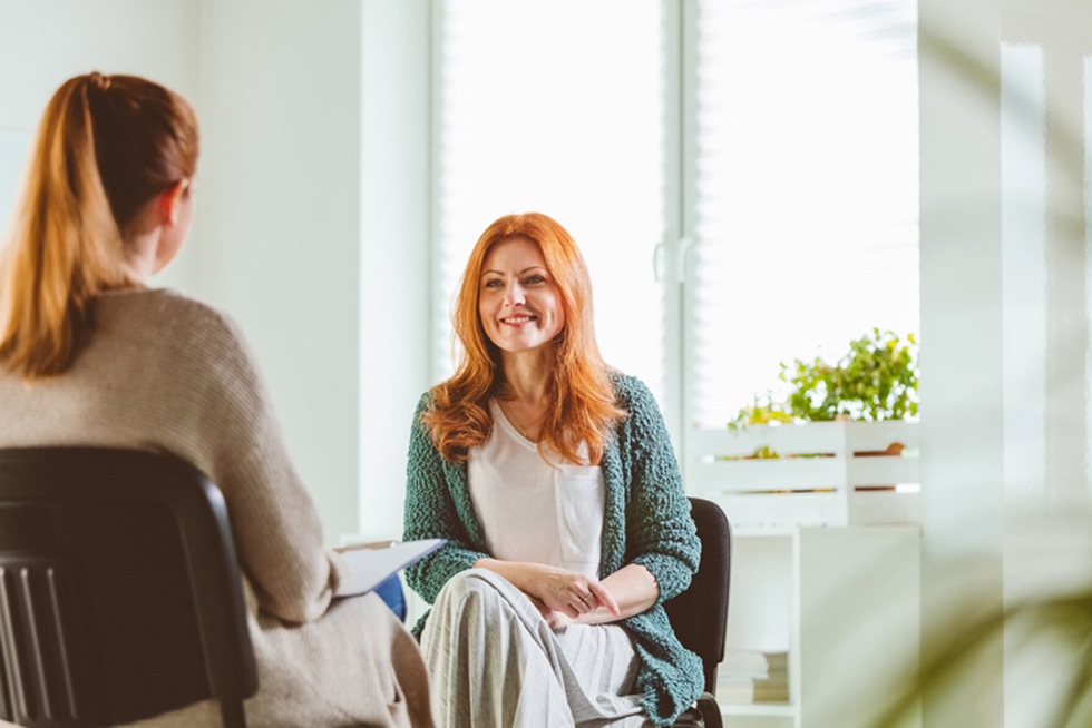 Two women sitting and talking in business setting.