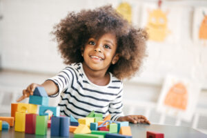 Happy kid playing with colorful blocks at a table.