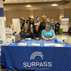 Coworkers at trade show booth for Suprass Behavioral Health.