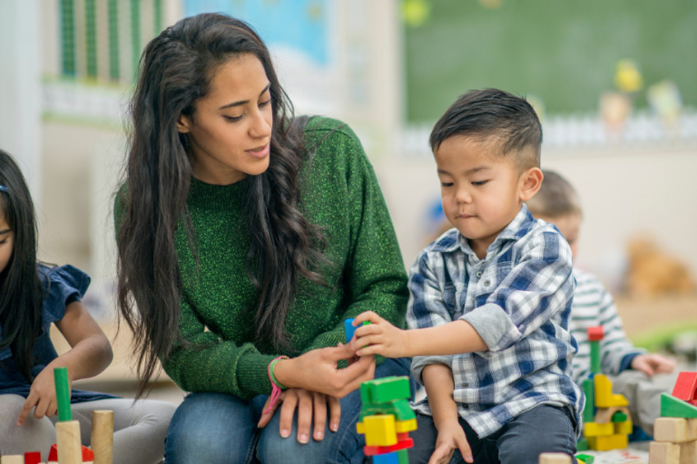 Mother and son play with blocks on the floor.