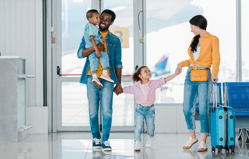 Family walking through airport holding hands.