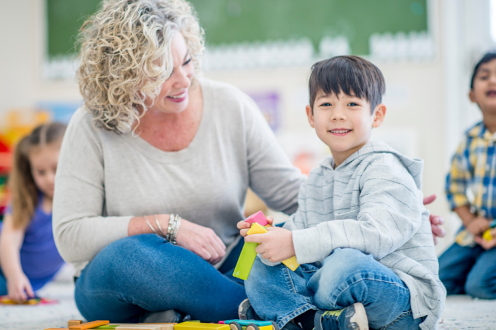 Mom and son play with colorful blocks on the ground.