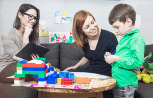 Child playing at table with blocks next to mom and doctor.
