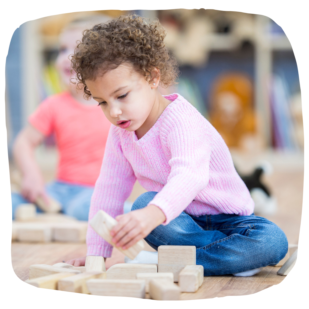 Little kid playing on the floor with wooden blocks.