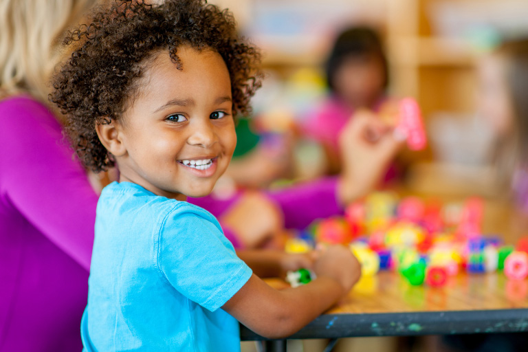 Young curly hair girl smiling while playing game at table.