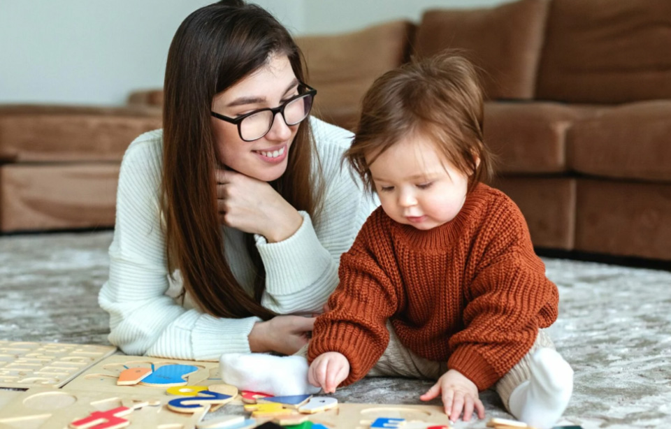 Mother and child on floor playing with letters.