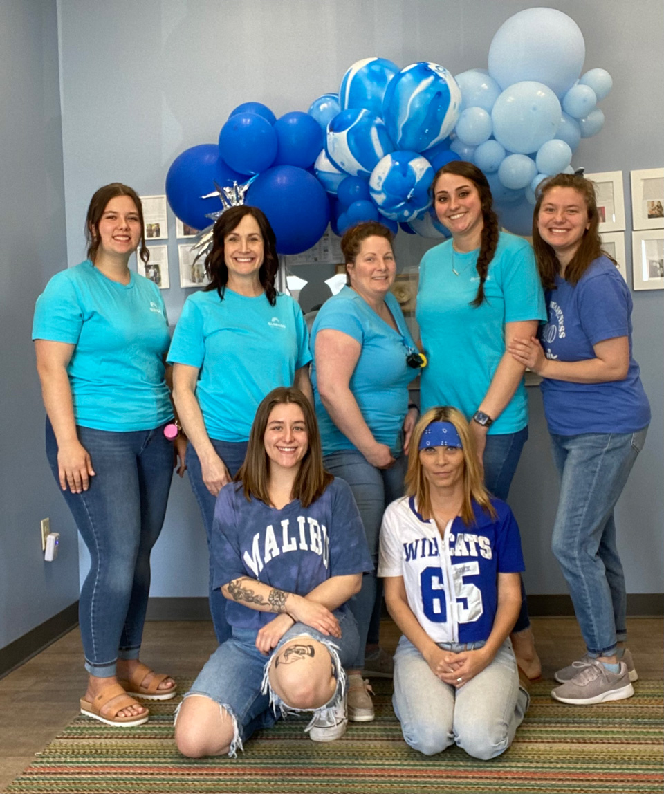 Employees in front of balloons at office.