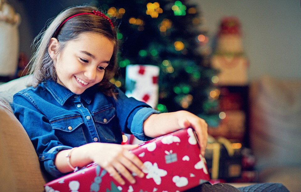 Child with Christmas gift inside home.