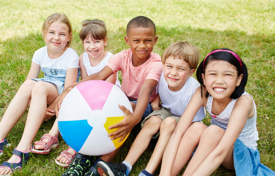 Happy children sitting outside on grass.