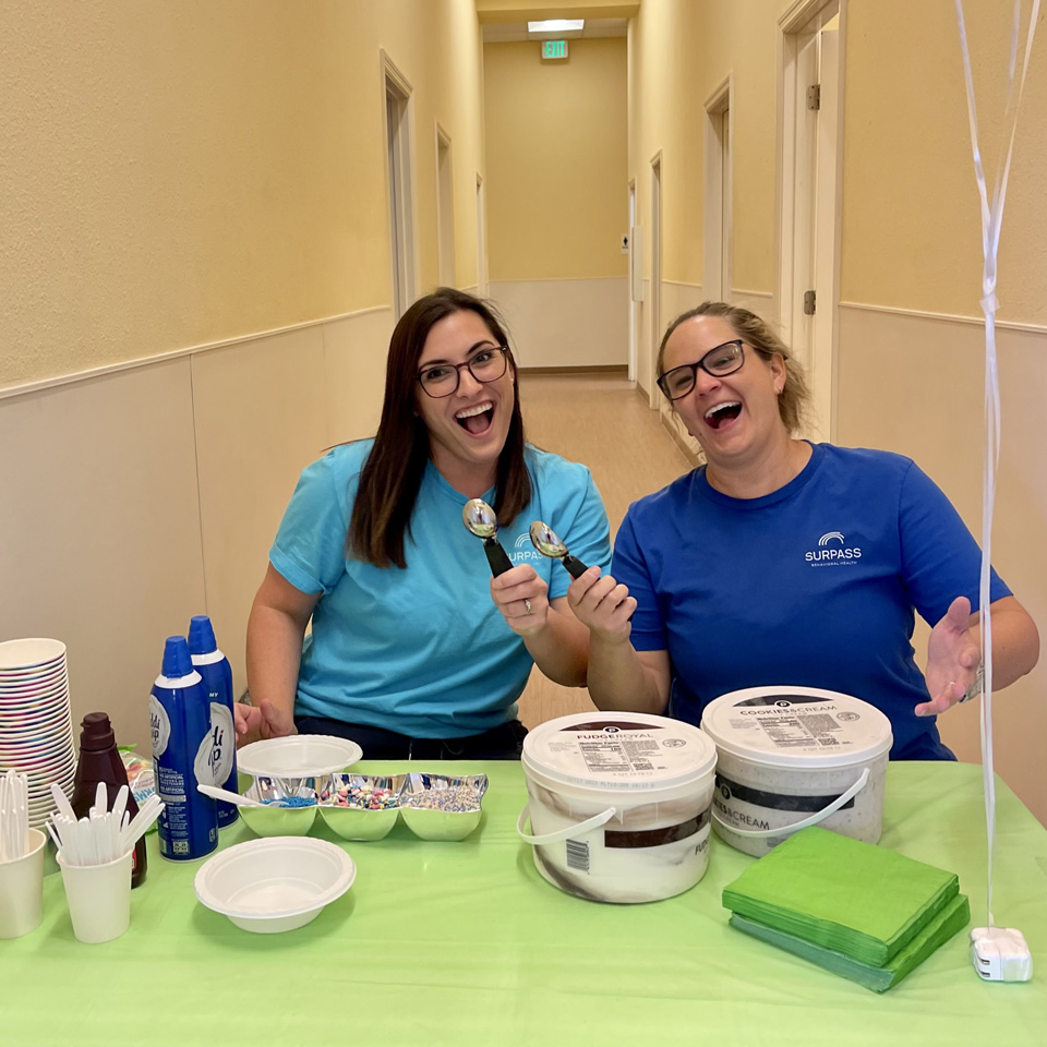 Two happy employees eating ice cream in business hallway.